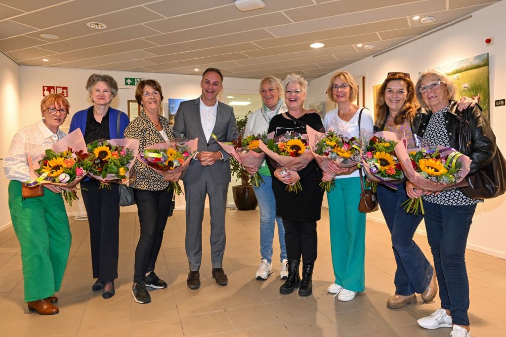 Wethouder Philippe van Ham staat met meerdere kunstenaars op een rij voor de foto. De kunstenaars hebben een bos bloemen vast.