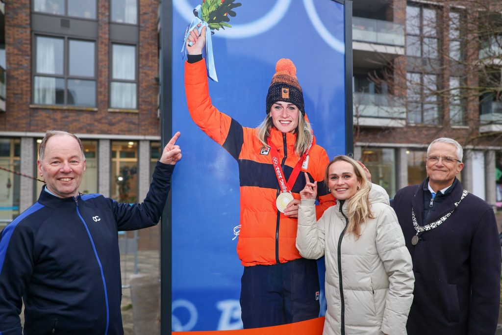 Wethouder Idso Brouwer staat links van de zuil en wijst naar de afbeelding van Irene. Voor de zuil staat Irene die naar haar afbeelding wijst. Rechts staat waarnemend burgemeester Pieter Dijkman.