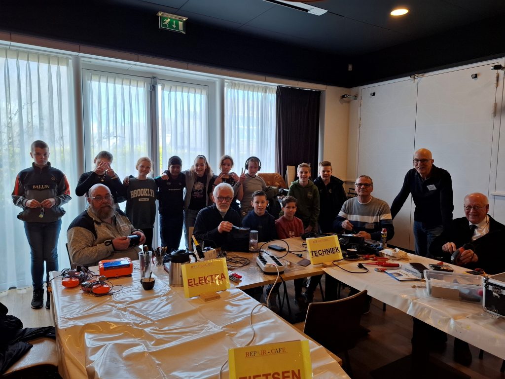 Kinderen van basisschool Uilenburcht staan samen met mannen van de repaircafé op de foto.