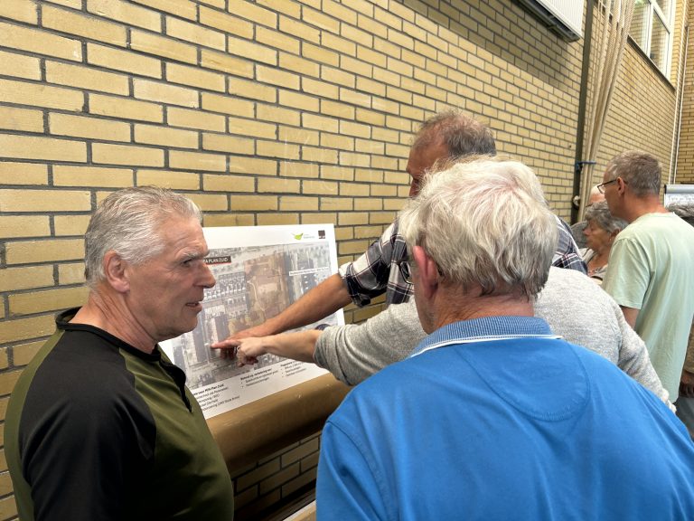 Foto van de inloopbijeenkomst waarop mensen te zien zijn die naar de plannen kijken.