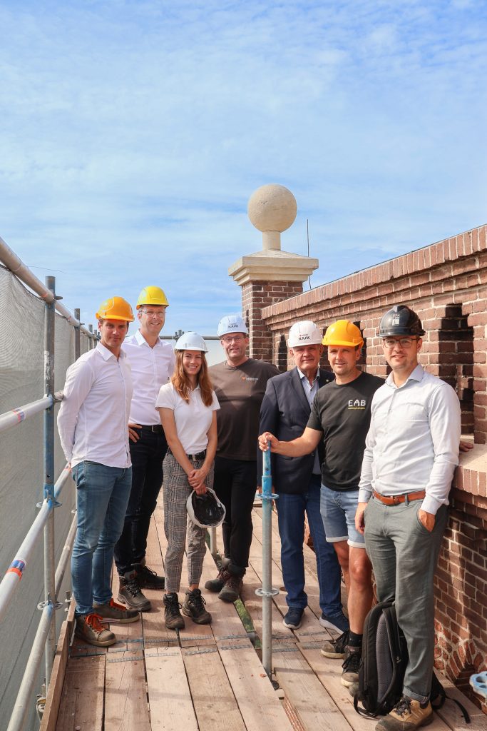 Met wethouder Marcel ten Have staan vertegenwoordigers van aannemersbedrijf E.A.B., Koedooder Metselwerk en TPAHG architecten bovenop de kerktoren van Hem.
