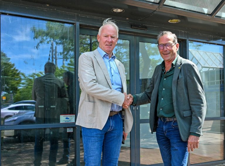 Jan Kuin van Kuin Vastgoedontwikkeling B.V. en wethouder Nico Slagter schudden elkaar de hand voor een van de gebouwen.