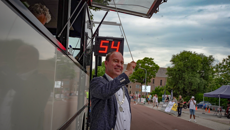 Burgemeester Bram Diepstraten trekt aan een touwtje om het startsignaal te geven aan de wielrenners