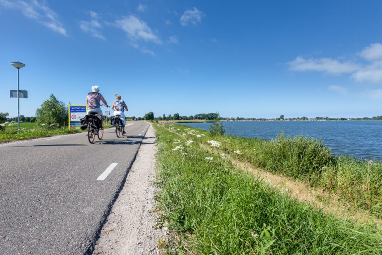 fietsers op de Zuiderdijk met een blauwe lucht. (bij het kruispunt naar Oostergauw, Venhuizen)