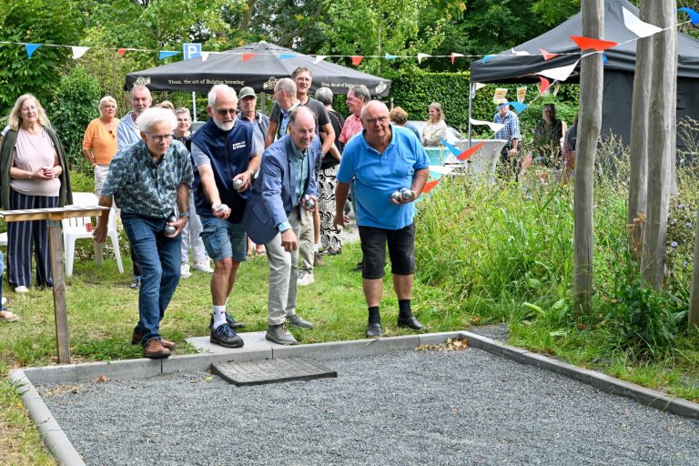 Wethouder Idso Brouwer gooit een van de ballen op de nieuwe jeu-de-boulebaan met drie inwoners.