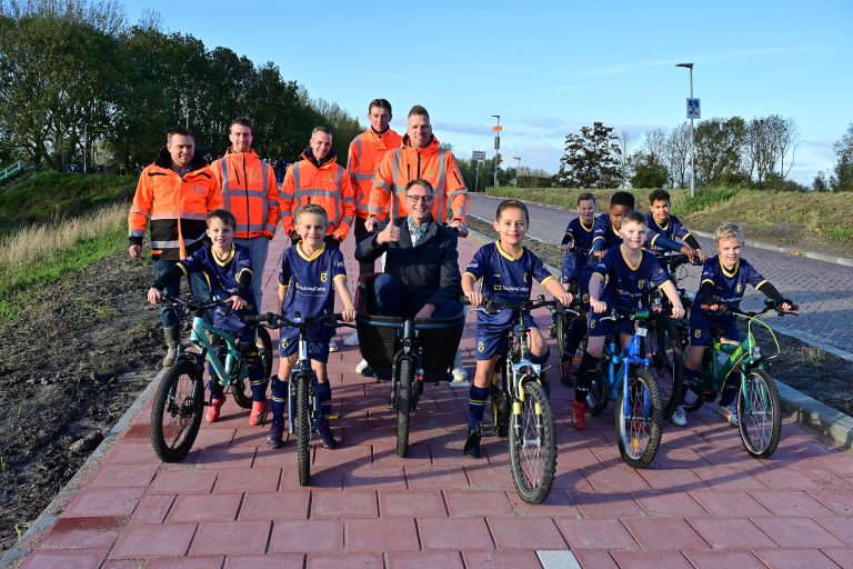 wethouder Bijman opent zittend in een bakfiets samen met jeugdleden van de voetbalvereniging het nieuwe fietspad