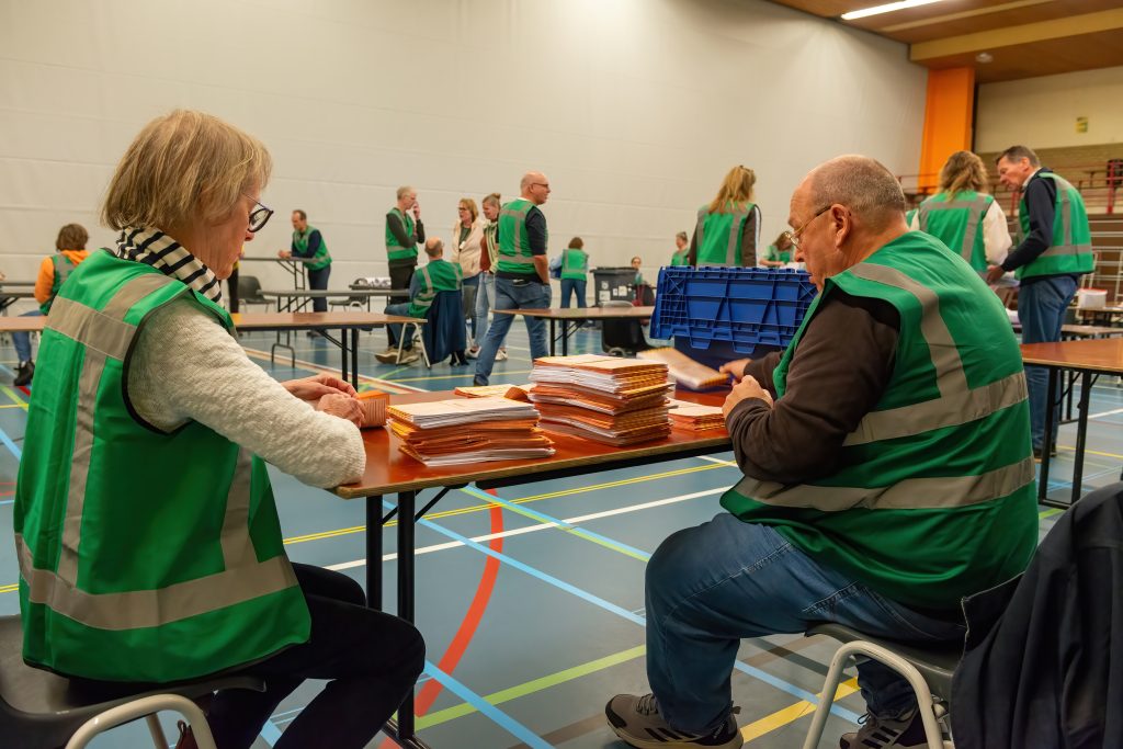 Vrijwilligers in groene hesjes tellen de stemmen in de Drecht