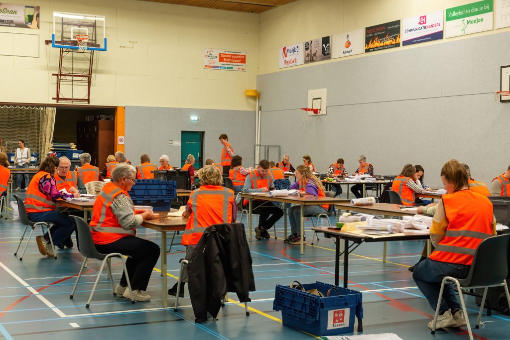 vrijwilligers in oranje hesjes tellen stemmen in de Drecht.