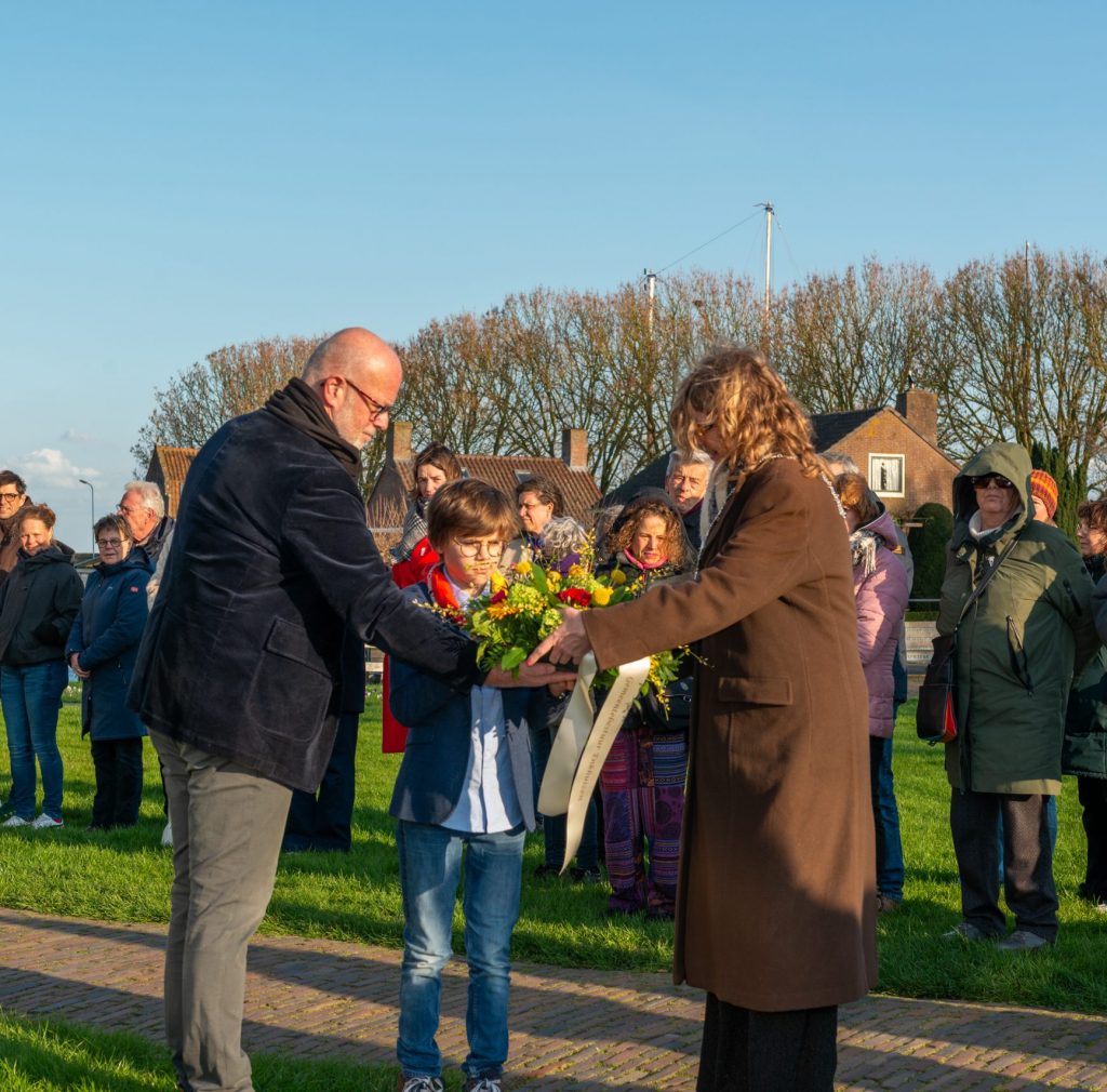 Burgmeester Hoekstra-Sikkema, kinderburgemeester Otto Schuit en wethouder Wim Hoogervorst houden het bloemstuk vast voor bij de gedenksteen.