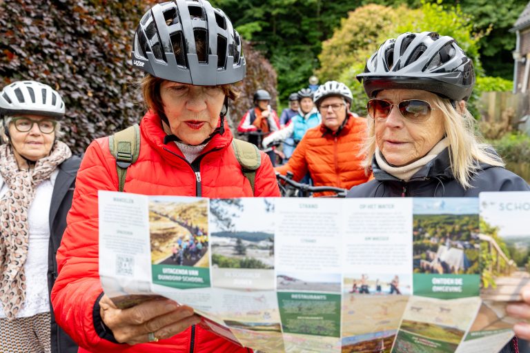 twee dames met fietshelm op bekijken een kaart een een grote folder